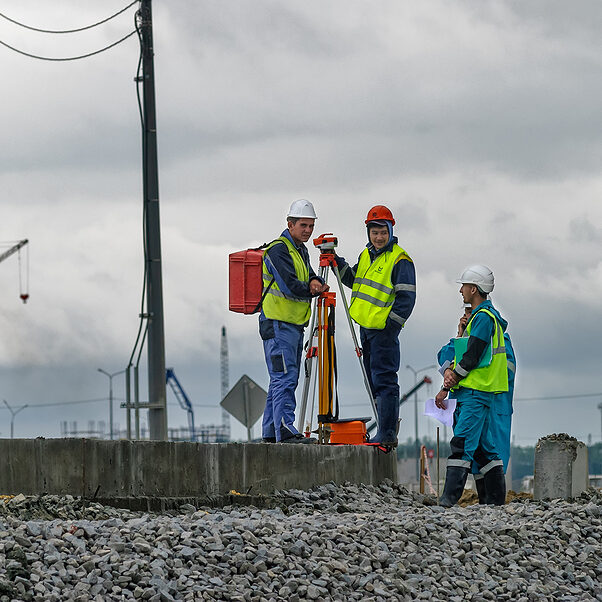 Tobolsk, Russia - July 15. 2016: Sibur company. Construction of plant on processing of hydrocarbons. Surveyor builders worker with theodolite transit equipment at construction site outdoors during surveying work