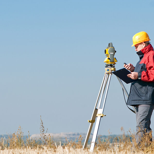 Surveyor worker making measurement in a field with theodolite total station equipment